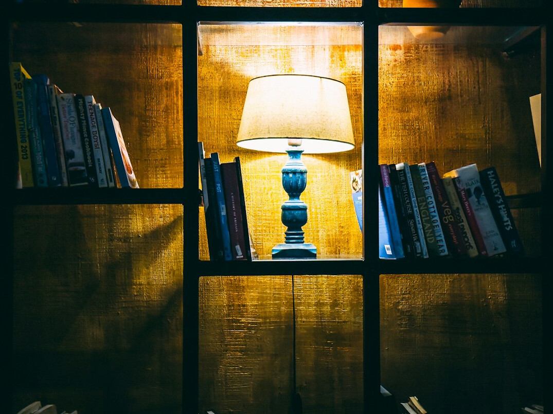 Atmospheric old library with tall wooden bookshelves and warm lamp light